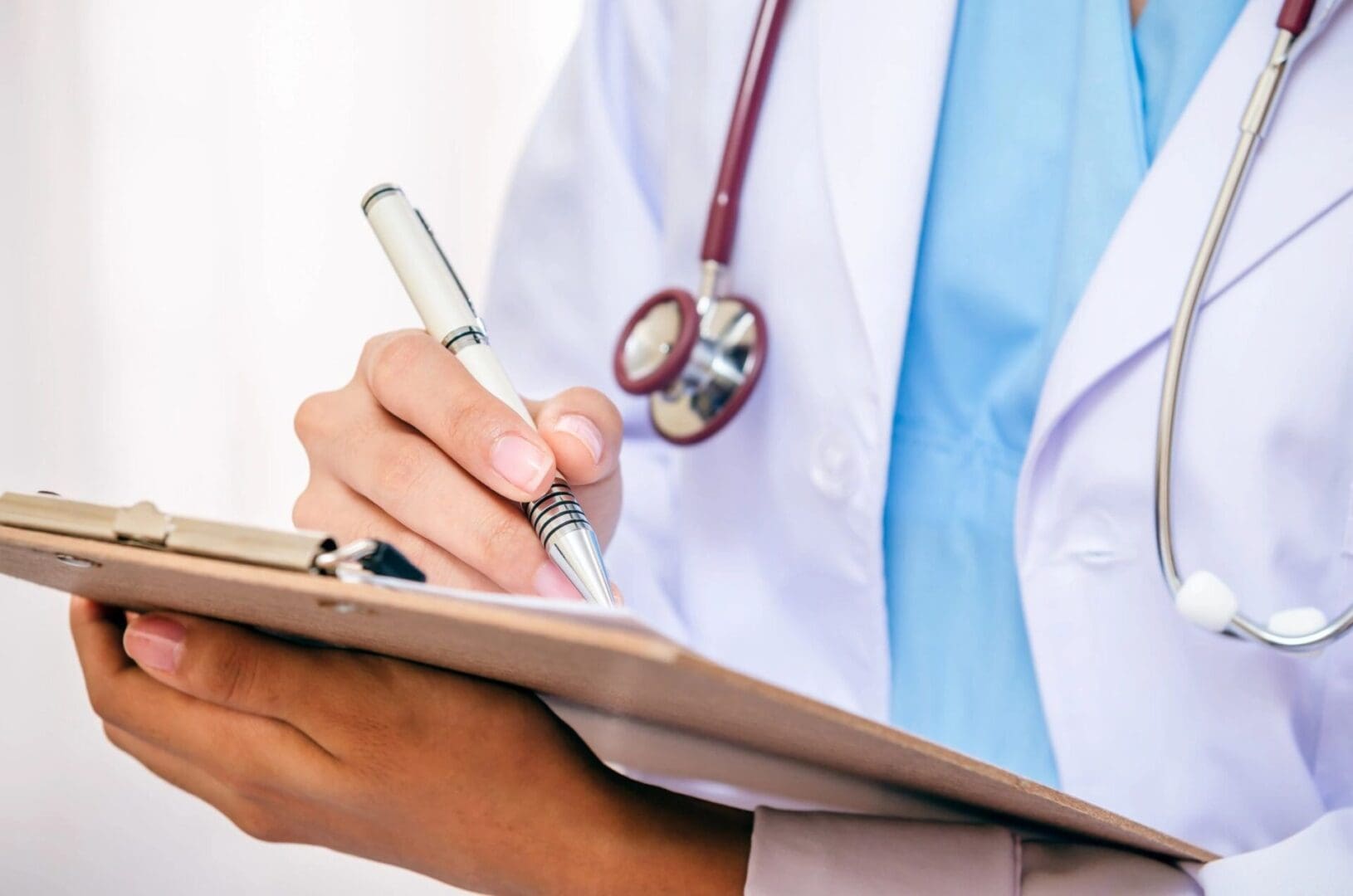 A doctor writing on a clipboard with a stethoscope.