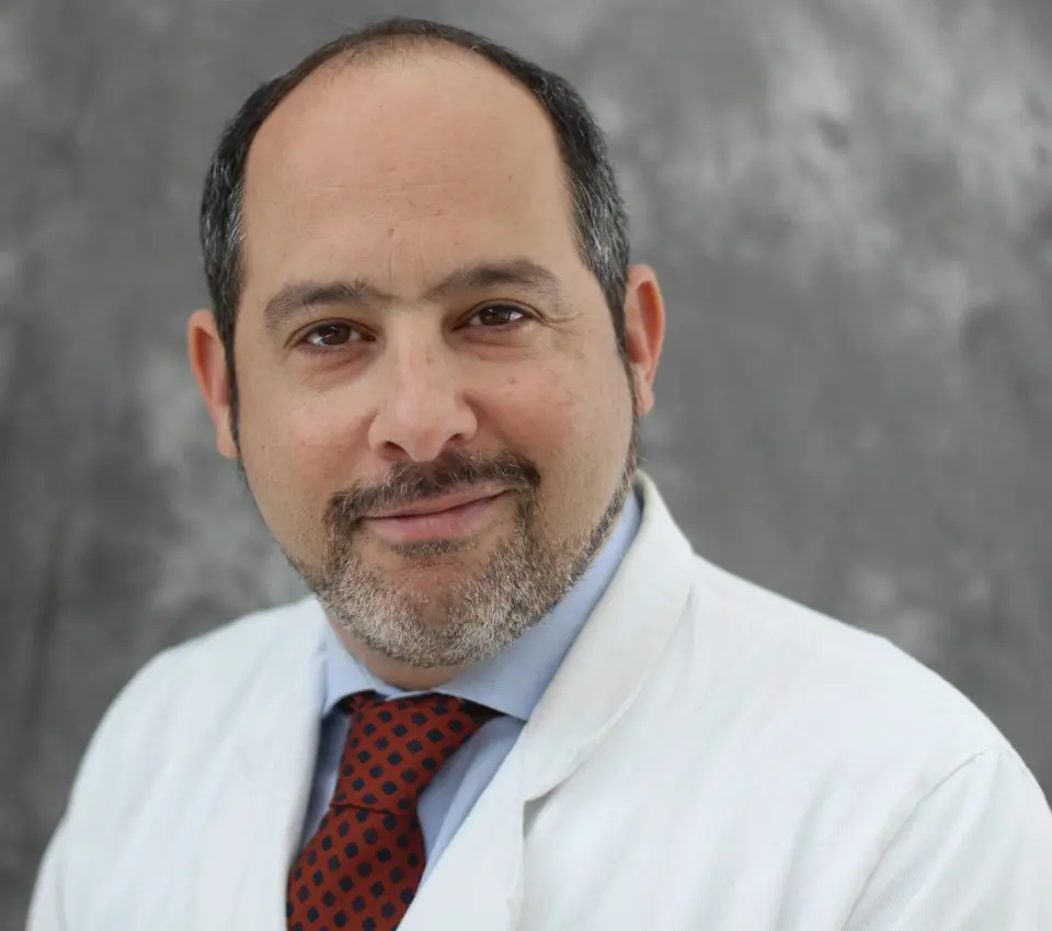 A man in a white lab coat is posing for a photo.